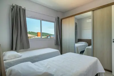 Uma cama ou camas num quarto em 2 suítes, sacada com churrasqueira em Bombas/SC