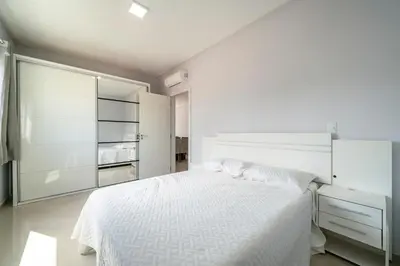 Uma cama ou camas num quarto em 2 suítes, sacada com churrasqueira em Bombas/SC