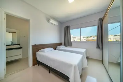 Uma cama ou camas num quarto em 2 suítes, sacada com churrasqueira em Bombas/SC