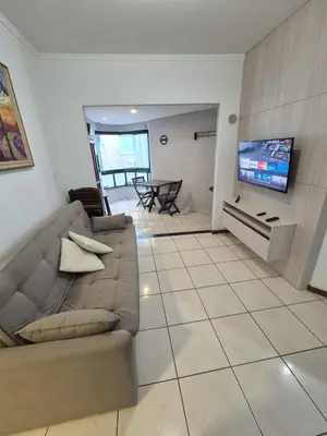 Uma televisão e/ou sistema de entretenimento em Apartamento pé na areia em Meia Praia com churrasqueira com vista mar