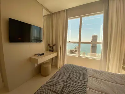 Uma televisão e/ou sistema de entretenimento em Apartamento vista ao mar em Meia Praia 3 suítes