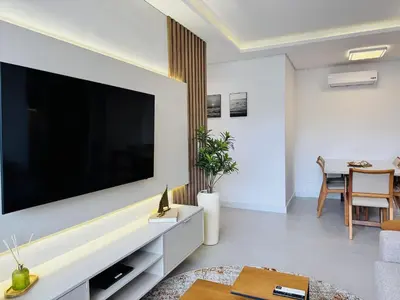 Uma televisão e/ou sistema de entretenimento em Oásis do Atlântico 303 A - Apartamento elegante na Praia de Palmas, em um condomínio clube completo.